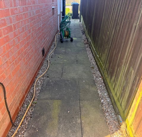 Alleyway between brick wall and fence before cleaning